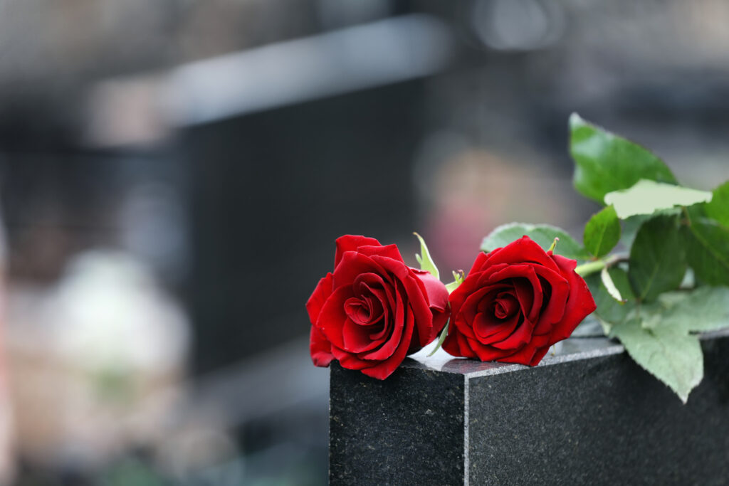 Red,Roses,On,Black,Granite,Tombstone,Outdoors,,Space,For,Text.