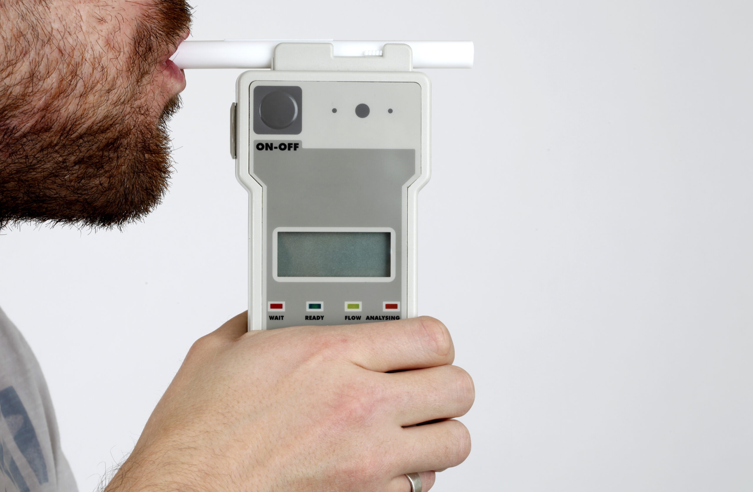 Young adult man blowing in police issue breathalyzer with blank screen allowing any reading you like.